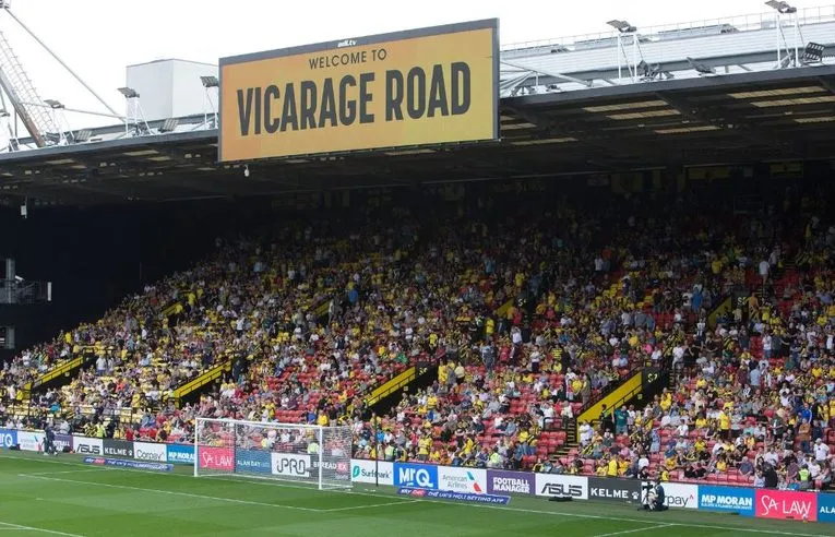 Cảnh sân Vicarage Road vào ngày diễn ra trận đấu, sôi động và đầy ắp người hâm mộ