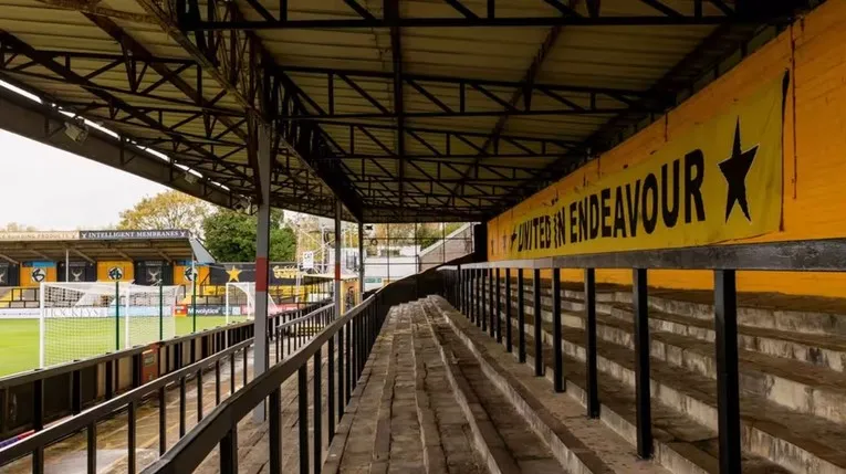 Hình ảnh các khu vực khán đài đứng tại Abbey Stadium, thể hiện không khí bóng đá truyền thống của sân.