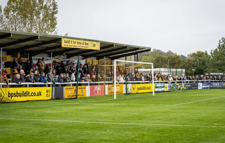 Hình ảnh khán đài phía sau khung thành sân New Windmill Ground trong một ngày thi đấu của Leamington FC, thể hiện không khí bóng đá địa phương sôi động.
