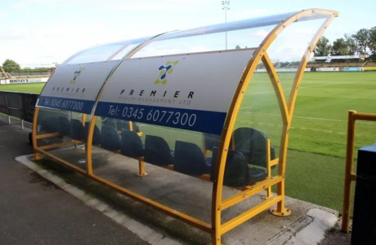 Khu vực cabin huấn luyện viên (Dugouts) sát sân cỏ tại Haig Avenue, gần gũi với cầu thủ.