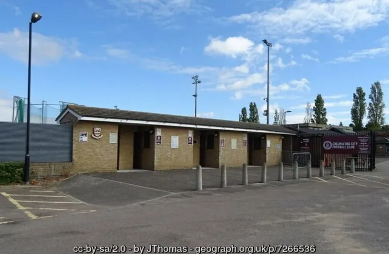 Lối vào chính của sân vận động Melbourne Community Stadium, sân nhà của Chelmsford City FC, với kiến trúc đơn giản và lối đi dẫn vào sân.